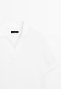 Biała koszulka polo z krótkim rękawem, kołnierzykiem i plisą z trzema guzikami, z czarną metką Massimo Dutti wewnątrz kołnierza.