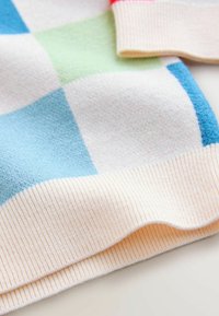 Sveter zo zmesi bavlny s kockovaným vzorom v svetlomodrej, zelenej a krémovej farbe. Má rebrované manžety a textúrovaný povrch.