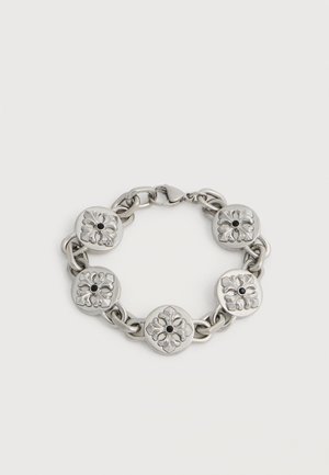 Silver chain bracelet with five round flower-engraved links, each featuring a small black center stone, clasp closure on a white background.