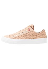 Sneakers in tela beige chiaro con texture intrecciata, suola in gomma bianca e sei fori per i lacci. Presentano un accento rosa vicino ai lacci.