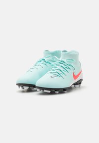 Crampons de football bleu clair avec une semelle noire, un swoosh Nike rose et une finition texturée ; présente un design de cheville haute et un système de laçage standard.