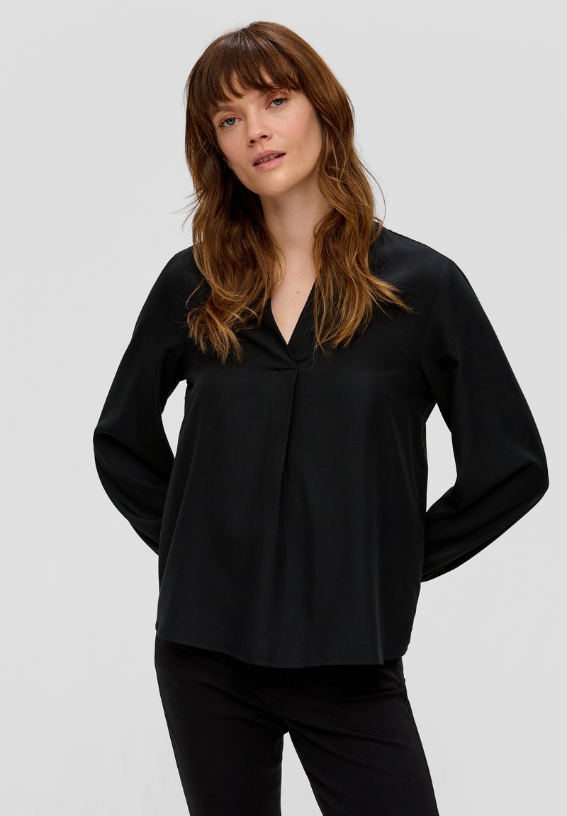 Schwarze Bluse mit langen Ärmeln und V-Ausschnitt, aus glattem Stoff gefertigt. Hat eine lockere Passform und dezente Fältchen am Vorderteil.