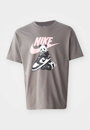 Szara bawełniana koszulka z grafiką przedstawiającą pandę siedzącą na butach Nike, z różowym logo Nike nad wzorem. Krótkie rękawy, okrągły dekolt.