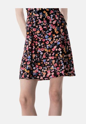 Zwarte rok met oranje, roze, paarse en witte bloemenprint gedragen door een staand persoon, bij de taille en knieën bijgesneden.