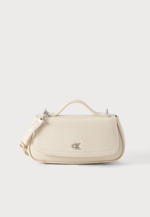 Kleine cremefarbene Handtasche mit Tragegriff, langem Riemen und silbernem CK-Logo auf der Vorderseite, auf einem schlichten hellen Hintergrund platziert.
