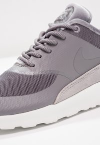 Grå sneakers med en blandning av mesh och mocka, rund tå, tjock vit sula och snörning framtill med grå snören.