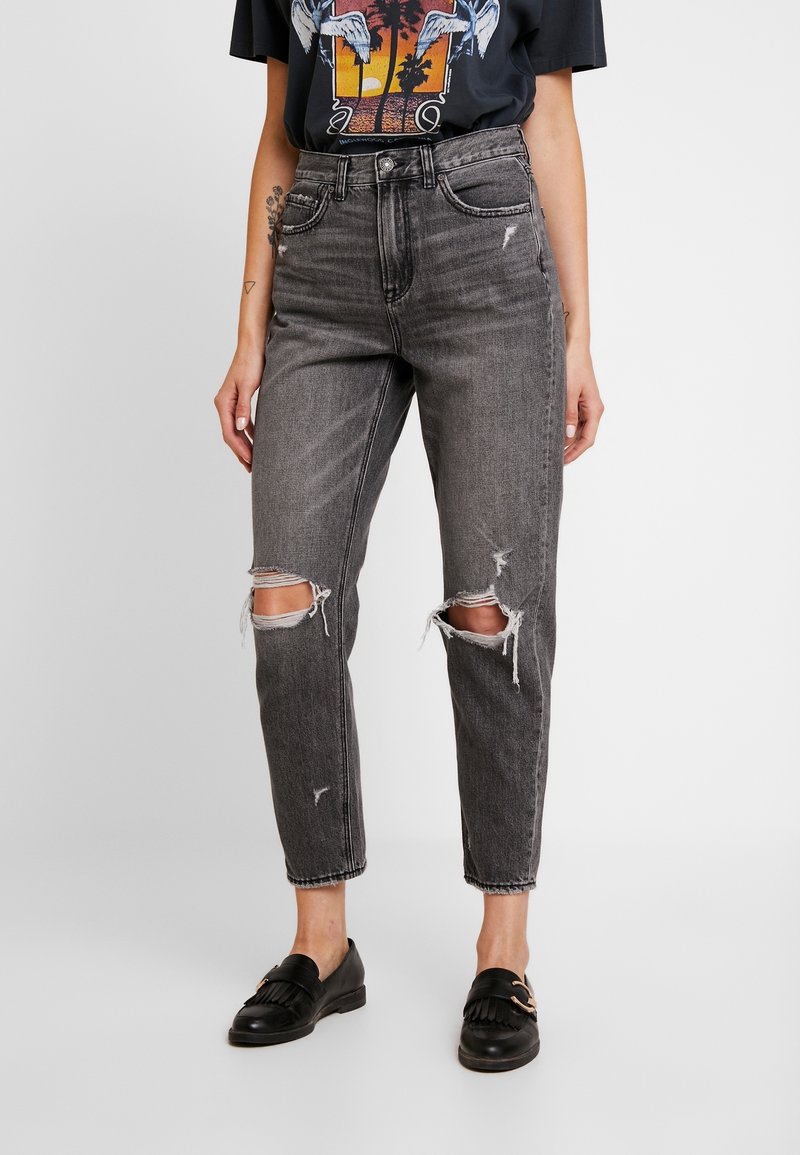 Höga svarta denimjeans med revor vid knäna, med en rak benpassform och subtil slitning överallt.