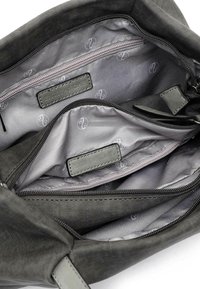 Intérieur d'un sac à main gris avec plusieurs compartiments, y compris une poche zippée. Doublure en tissu lisse avec un motif de logo subtil et des accents en cuir.