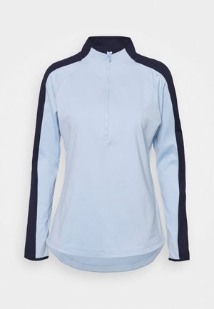 Pullover à manches longues bleu clair avec un col zippé, présentant des panneaux latéraux bleu marine. Tissu doux, coupe décontractée et design à ourlet courbé.