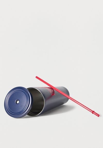 Σκούρος μπλε μεταλλικός κύπελλος με αποσπώμενο καπάκι και μακρύ κόκκινο καλαμάκι που ακουμπά σε λευκή επιφάνεια.