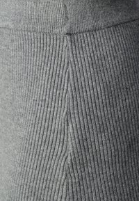 Grå ribbad tyg med vertikal struktur, som har detaljerade sömmar, vilket skapar en figursydd siluett som är lämplig för avslappnad klädsel.
