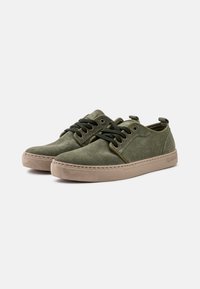 Zelene sneakers od sueda s niskim profilom, okruglim vrhovima i kontrastnim bež gumiranim potplatima. Imaju vezivanje na vezice i metalne rupice.