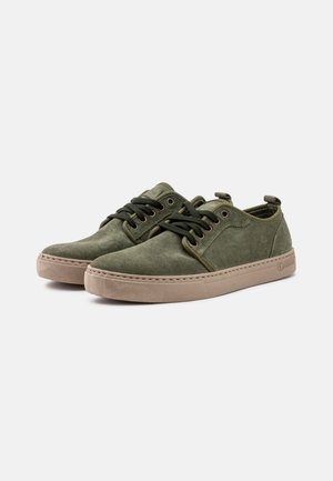 Zapatillas de ante verde con un perfil bajo, puntas redondas y suelas de goma beige en contraste. Presentan un cierre de cordones y ojales de metal.