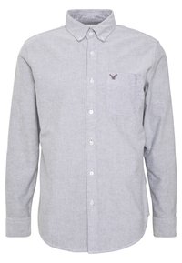 Světlá šedá košile na knoflíky s límečkem, dlouhými rukávy a kapsou na levé hrudi, zdobená malým vyšitým logem.