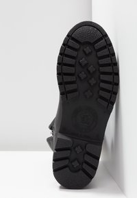 Semelle de botte noire avec un motif de bande de roulement profond, un logo circulaire, et le texte « Natural Life & Style Since 1989, Made in Spain » visible au-dessous.