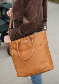 Hnědá kožená taška přes rameno s texturovaným povrchem, vybavená dvěma pevnými držadly, kapsou na zip a dekorativními vzory prošití.