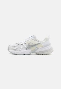 White athletic shoe featuring a mesh and synthetic upper, textured accents, cushioned midsole, and patterned rubber outsole.
