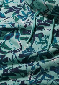 Hrejivá mikina s kvetinovým vzorom v jemnej teal farbe s námorníckymi a zelenými botanickými dizajnmi, so šnúrkou na kapucni a stredne ťažkým materiálom.