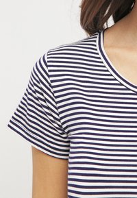 T-shirt de algodão listrado em azul-marinho e branco, com decote redondo e mangas curtas, apresentando uma textura suave e um corte casual.