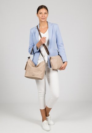 Beige suede shoulder bag and small handbag with brown straps, displayed against a plain backdrop. Features smooth textures and minimalist design.
