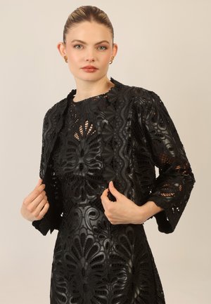 Black lace dress with floral cutouts and a matching cropped jacket. The material is textured leather, featuring intricate patterns and scalloped edges.