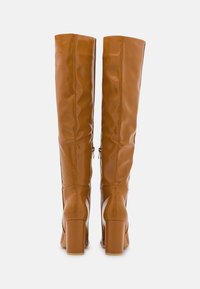 Botas de tacón alto marrones, por encima de la rodilla, hechas de un material sintético brillante, con un zipper en el lateral y un tacón cuadrado grueso.
