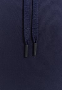 Tejido azul marino con dos cordones ajustables con puntas de plástico negro, que presenta una textura suave y un color uniforme.