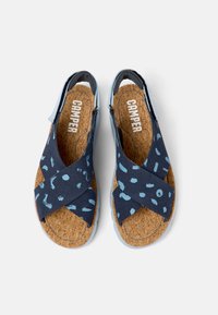 Tummansinisiä sandaaleja, joissa on vaaleansinisiä kuvioituja hihnoja, korkkijalkapohja ja harmaa kumipohja. Ristihihnasuunnittelu mahdollistaa avoimen kantapään.