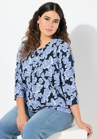 Kukkakuosiset puserot, joissa on kolme neljännestä hihaa ja sinisiä sävyjä tummansinisellä taustalla. Silkkinen kangas, rento malli.