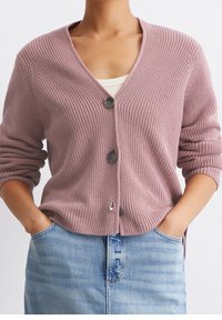 Krótki rękaw, jasnoróżowy, dziany kardigan z dekoltem w kształcie litery V, trzema guzikami i prążkowaną strukturą. W zestawie z jasnoniebieską spódnicą dżinsową.