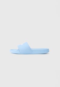 Sandalie ușor albastre, cu slip-on, dotate cu o curea lata care prezintă un logo brodat alb de crocodil și marcaj Lacoste pe marginea tălpii.