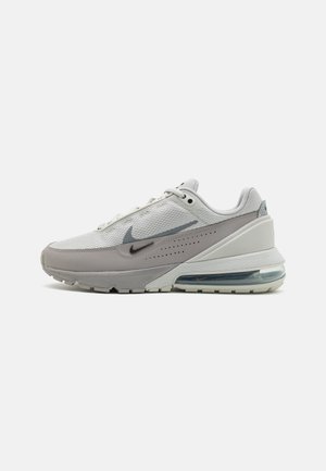 Biało-szary sneaker Nike Air Max z cholewką z siateczki, widoczną podeszwą z poduszką powietrzną i podwójnymi logo Swoosh po boku, pokazany z profilu na białym tle.