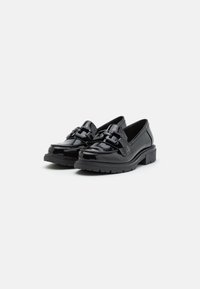 Sort patenterede læderloafer med en chunky sål, prydet med en fremtrædende sløjfedetalje på overdelen og en glat, blank overflade.