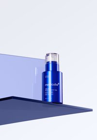 Medicube One Day Exosome Shot 7500 in una bottiglia cilindrica azzurro brillante con erogatore trasparente, etichettata con testo bianco, su una mensola blu scuro.