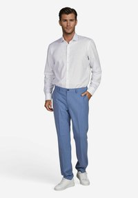 Witte lange mouwen overhemd met knopen, gecombineerd met lichtblauwe op maat gemaakte broeken en witte sneakers. De outfit heeft een slim fit design en een soepele textuur.