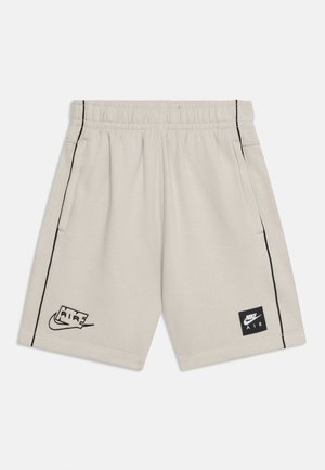 Shorts Nike Air color beige chiaro con fascia elastica in vita, piping laterale nero, tasche frontali e loghi Nike Air sulle gambe sinistra e destra.