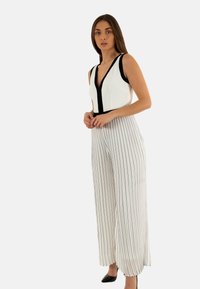 Monos de rayas en blanco y negro con un escote en V profundo, diseño sin mangas y piernas anchas. Tejido suave con rayas verticales.