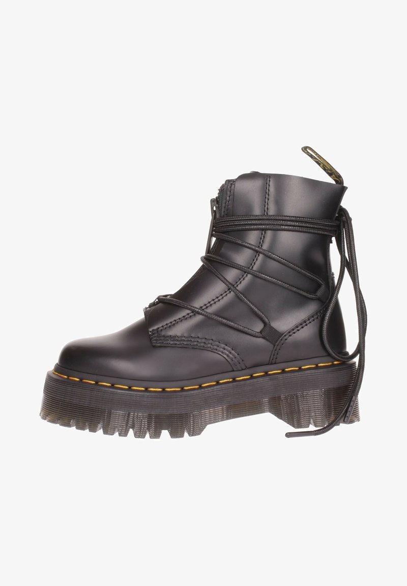 Botte plateforme en cuir noir avec semelle épaisse texturée, surpiqûres jaunes et longs lacets enroulés et noués à l’arrière.