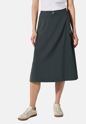 Donkergrijze knielange rok met een elastische tailleband, zijzakken en een gladde, lichte stof. Gecombineerd met lichtgekleurde sneakers.