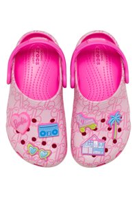 Zuecos rosas con charms temáticos de Barbie que incluyen un corazón, una radiocassette, gafas de sol, un patín de ruedas, una palmera y un patrón de casa de muñecas en los zapatos.