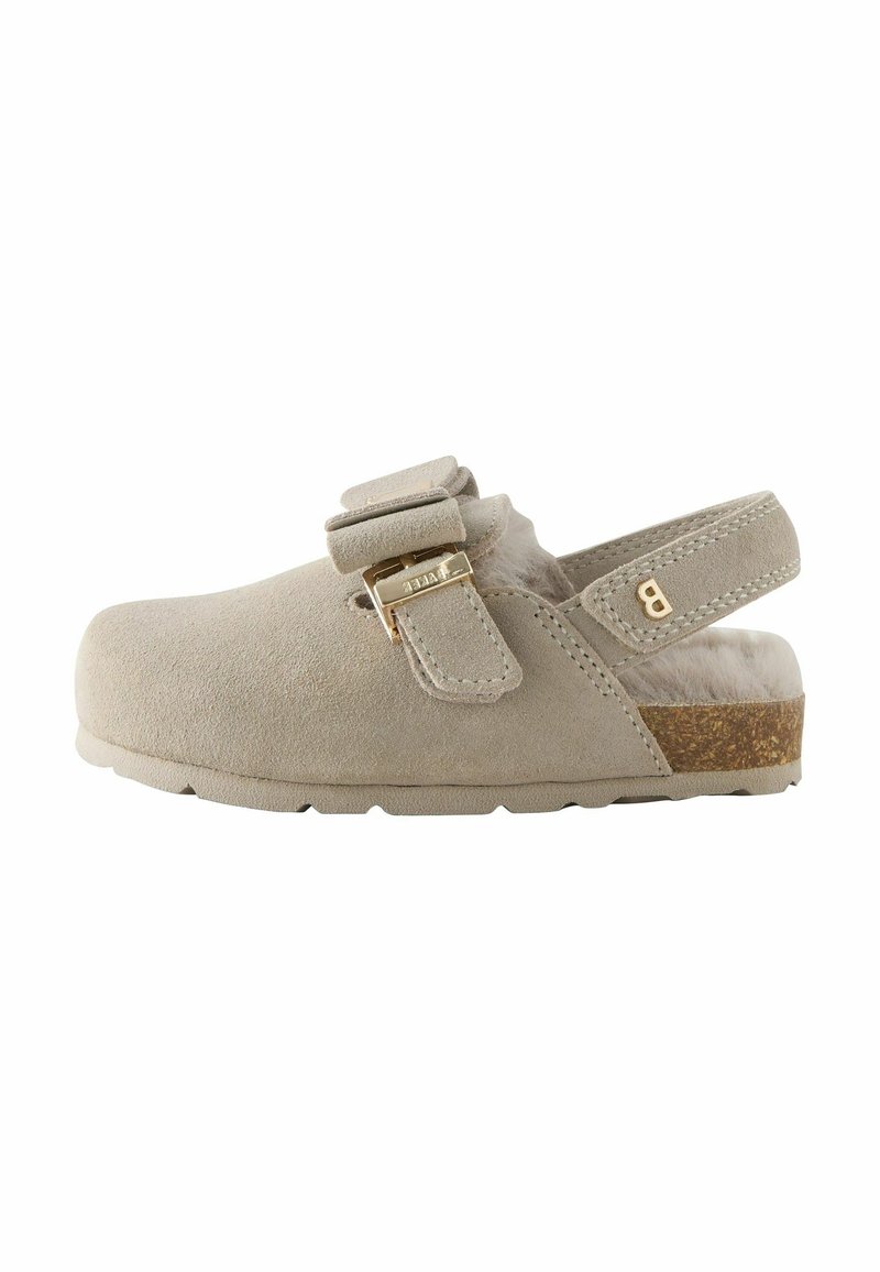 Sabots en suède beige avec une sangle et une boucle dorée, dotés d'une semelle en liège. La vue de côté met en avant leur style décontracté et leur confort.