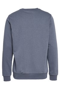 Felpa grigia con texture a coste, collo rotondo e maniche lunghe. Presenta un orlo e polsini flessibili, senza loghi o motivi visibili.