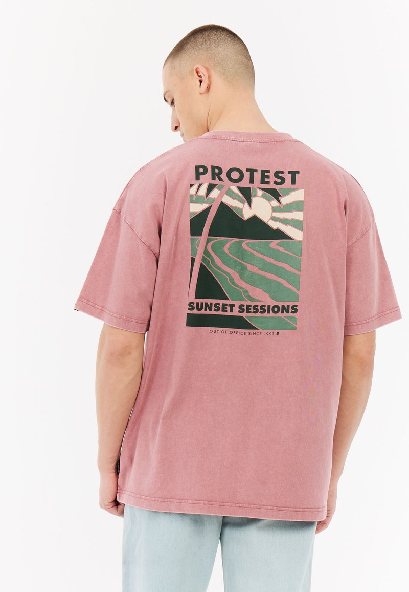 Roze katoenen oversized t-shirt met een grafisch ontwerp van palmbomen, bergen en een zon. Korte mouwen en een ontspannen pasvorm met een ronde hals.