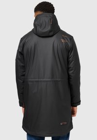 Černý voděodolný dlouhý kabát s kapucí, s úzkým pasem, minimalistickým designem a oranžovým logem na zadní straně.