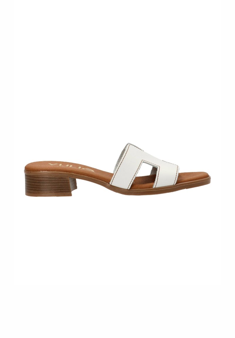 Sandal de deslizamiento blanco con una correa curva que presenta recortes abiertos, sobre una plantilla texturizada en tono marrón y un tacón bajo y cuadrado.