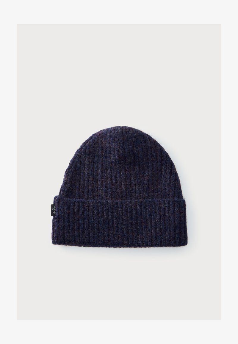 Bonnet en tricot côtelé bleu marine foncé avec revers plié et petite étiquette noire sur le côté, présenté sur un fond clair uni.