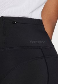 Svart høytalende leggings med en jevn tekstur. Har subtile sømdetaljer og en "KARI TRAA"-logo nær livet.