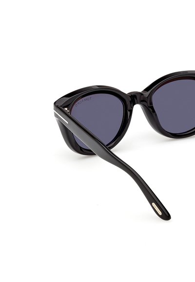 Ochelari de soare negri, forma cat-eye, cu lentile închise la culoare și un accent argintiu pe braț, marcați cu "Tom Ford" pe capătul brațului.