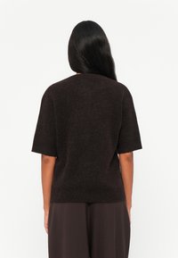 Dark brown knitted sweater with short sleeves, a round neckline, and a soft texture, viewed from the back against a white background.