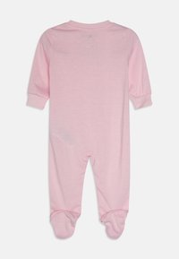 Un traje de una pieza rosa de manga larga con pies, de textura suave, escote redondeado, puños elásticos y sin patrones o herrajes visibles.